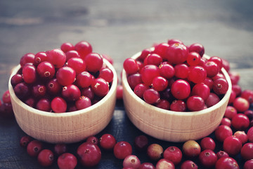 Fresh juicy cranberry in wooden round bowls on a table, close up