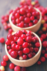 Fresh juicy cranberry in wooden round bowls on a table, close up