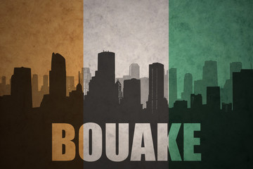 abstract silhouette of the city with text Bouake at the vintage ivorian flag © luzitanija