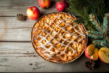 Traditional american apple pie on rustic wooden table, with apple. Near the Christmas tree branches and pine cones