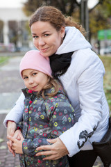 Fototapeta premium Portrait of Caucasian mother and youthful daughter embracing in autumn cold park