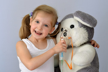 Child, kid (girl) with an inhaler (nebulizer) makes the procedure a soft toy.
