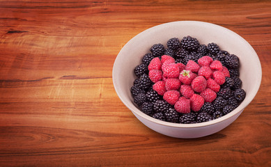 Ceramic plate with heart shaped berries on the right of the wooden table with clipping path. Top side view. Top side view.