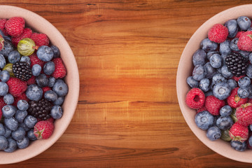 Brown ceramic plates with berries on the sides of the wooden table with clipping path. Top view.