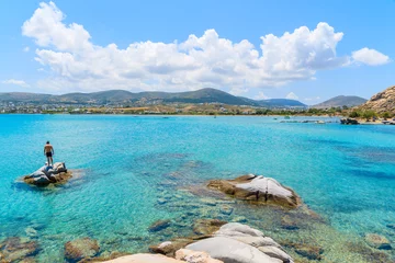 Papier Peint photo autocollant Île Jeune homme non identifié debout sur un rocher dans l& 39 eau de mer turquoise cristalline de la plage de Kolymbithres, île de Paros, Grèce