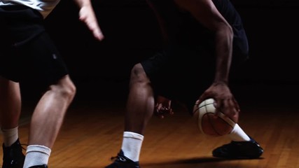 A basketball player challenges a defender and tries to dribble the ball past him