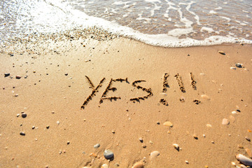 the inscription on the sand near the sea on a sunny day