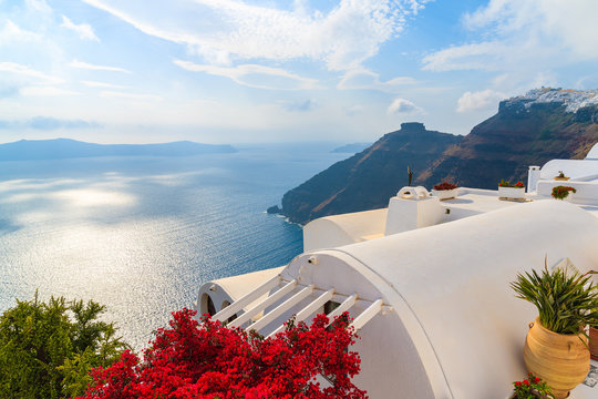 A view of caldera and sea from house roof decorated with red flowerrs in Firostefani village, Santorini island, Greece