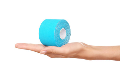 Female hand holding special physio tape roll on white background - obrazy, fototapety, plakaty