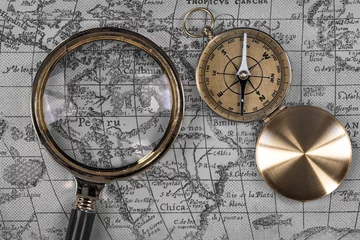Fotobehang top view, vintage marine compass and magnifier on old map, close-up © serikbaib