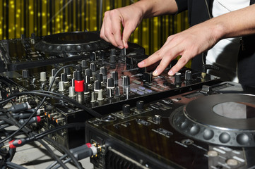 DJ at dance party mixes track on sound mixer, nightclub with striped yellow interior, nightlife entertainment industry