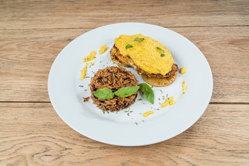 Chicken fillet with pineapple and curry sauce, served with rice on a white plate on old wooden table