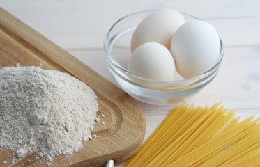 chicken eggs, spaghetti, flour on a white background