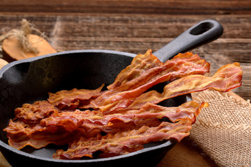 Hot fried bacon pieces in a cast iron skillet