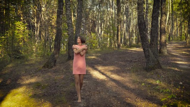 Young girl in a pink dress is walking in the woods