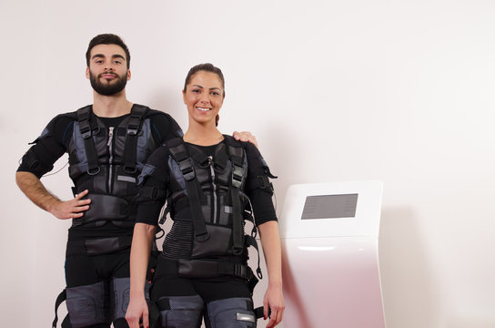Beautiful young man and woman in suits for electro muscle stimulation EMS. Selective focus on man