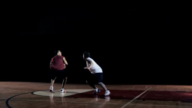 A basketball player goes against a defender and shoots a jump shot
