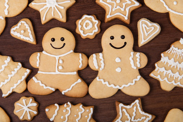 Christmas homemade gingerbread couple, firs, stars cookies over wooden background
