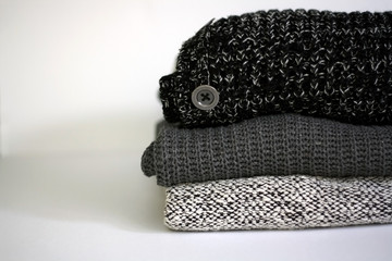 Stack of three chunky grey sweaters. Selective focus.

