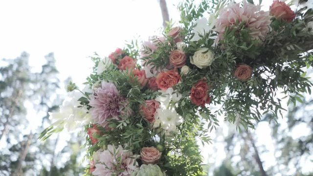 Outdoor wedding ceremony decoration before reception. Beautiful flower composition on arch in sunlight.