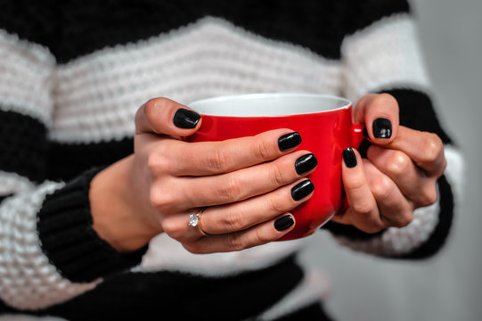 girl's hands holding a red cup of tea