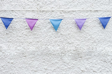 Colorful Party flags bunting hanging on white wall background. Minimal hipster style design.