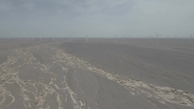 Flying over a dry riverbed towards a massive wind energy farm in the deserts of Gansu in central China