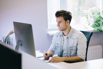 Looking from the working men in the office. Stylish designer at work sitting. Focused on his job