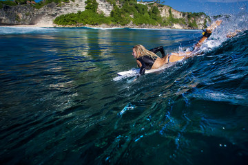 Beautiful sport model young blonde woman in bikini surfing in Bali in the Indian Ocean on the...