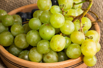 Green and black grapes in a wooden plate