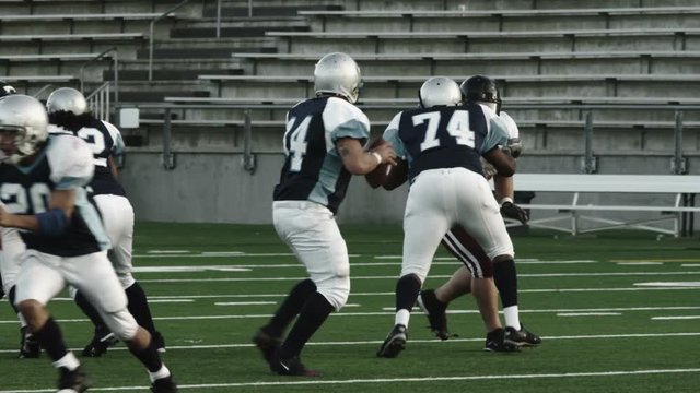 A quarterback snaps the ball and gets sacked by a defender