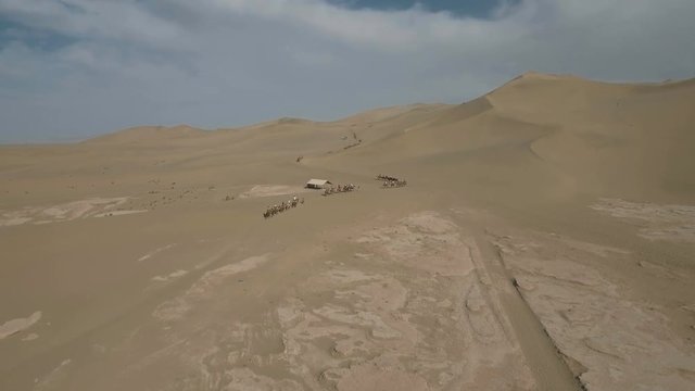 Aerial view of Chinese tourists riding camels through the deserts near Dunhuang