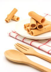 tong muan (a type of rolled wafer, a traditional dessert in Thailand) with Cutlery Set on white plate over a white background