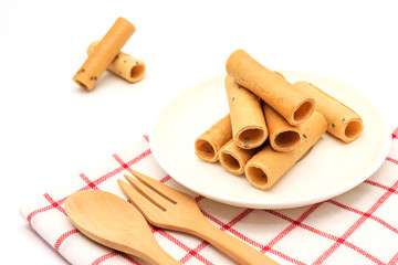 tong muan (a type of rolled wafer, a traditional dessert in Thailand) with Cutlery Set on white plate over a white background