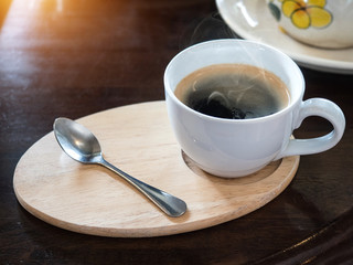 Warm cup of black coffee on wooden table background.
