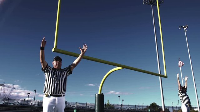 Two referees raise their hands over their heads after a field goal