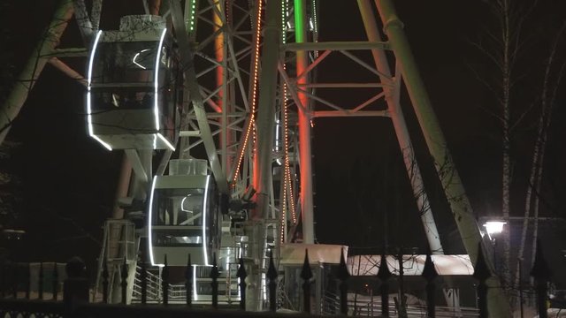 Ferris wheel rotating at amusement park under dark night sky
