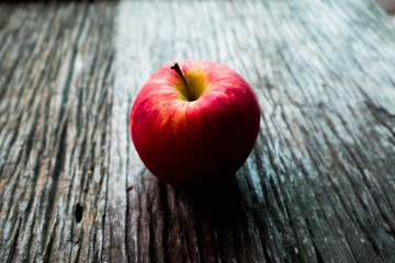 Apple with shadow on wooden background.