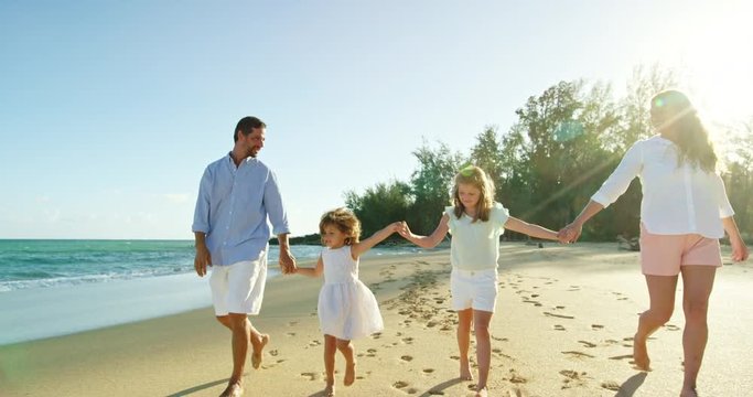 Happy mixed race family enjoying morning walk on the beach