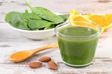 Ingredients and fresh cocktail from spinach on wooden background, healthy nutrition