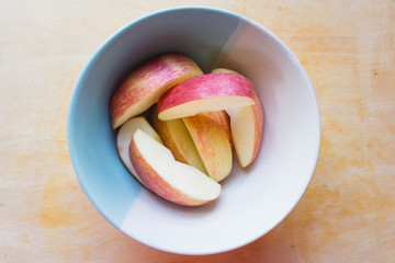 Red apple gala slice in a bowl on tamarind wood cutting board