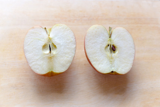 Red apple gala sliced in half on tamarind wood cutting board
