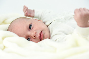 baby lying on a bed with towel