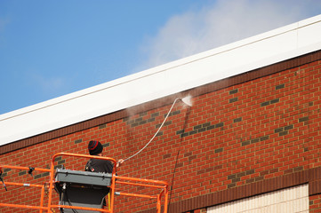 outdoor worker cleaning the exterior wall of building through pressure water