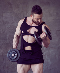 Muscular man doing biceps workouts with dumbbells.