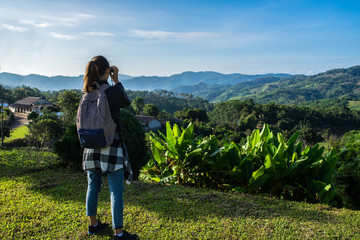 The tourist on the tea field looks in the field-glass at mountains. To look in a distance. The girl with the field-glass dressed vdinsovy trousers, a shirt and a backpack