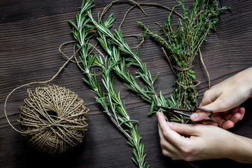 thyme and rosemary on wooden background with hands top view