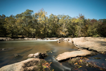 a river in South Carolina with a small waterfall and trees in the background