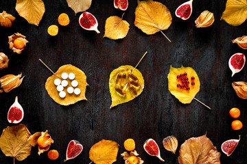 autumn leaves and sliced fruit on wooden background top view