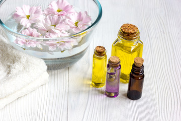 flowers in bowl and oil on wooden background
